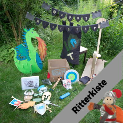 Inhalt der Geburtstagskiste zum Thema Motto "Ritter". Zu sehen sind die Wimpelkette, der Aufstell-Drache, Stuhl-Husse, Schokokuss-Schleuder, und vielem mehr...